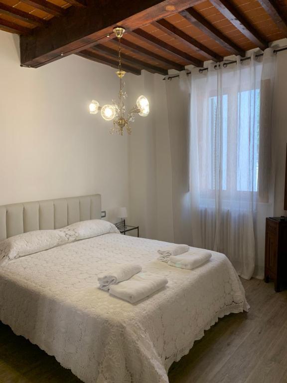 una camera da letto con un letto con lenzuola bianche e un lampadario a braccio di Fonte alle Ninfe B&B a Castiglione dʼOrcia