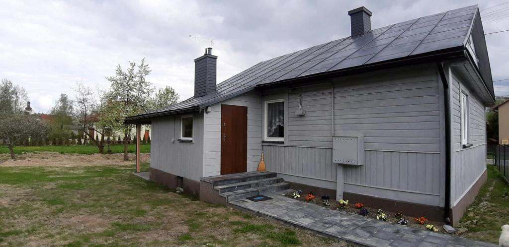 een klein grijs huis met een raam en een deur bij Apartament - Jurczak in Narol