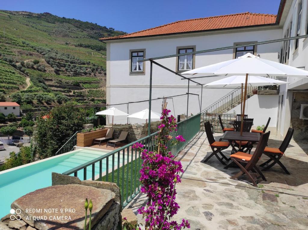 a house with a swimming pool and a table and umbrella at Quinta da Travessa - Douro in Covelinhas