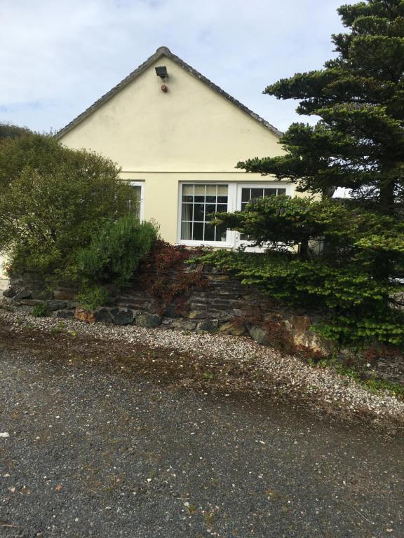 uma casa branca com uma janela numa parede de pedra em Down Ende House Accommodation em Looe