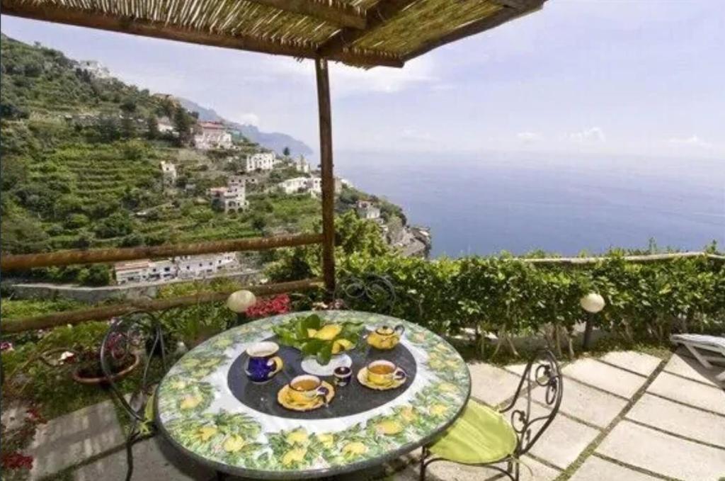 een tafel en stoelen op een patio met uitzicht op de oceaan bij Mariuccia House in Amalfi