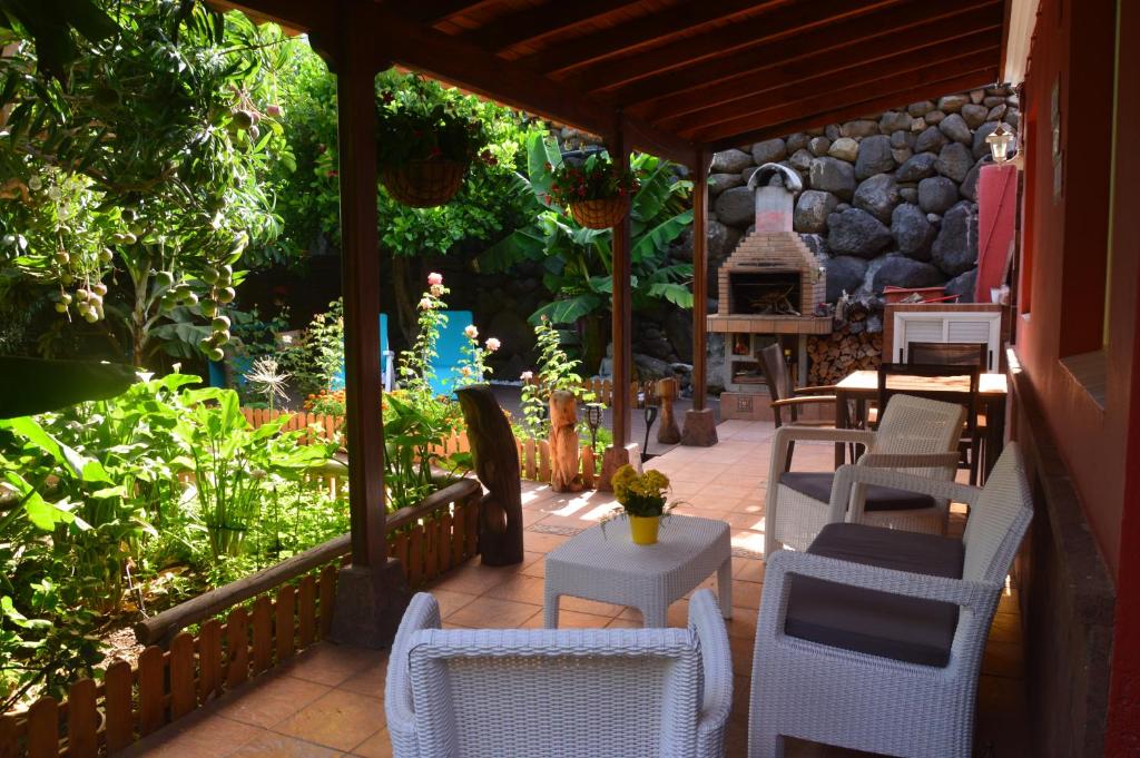 un patio con sillas, mesas y una pared de piedra. en Holiday House Tia Lila, en San Sebastián de la Gomera