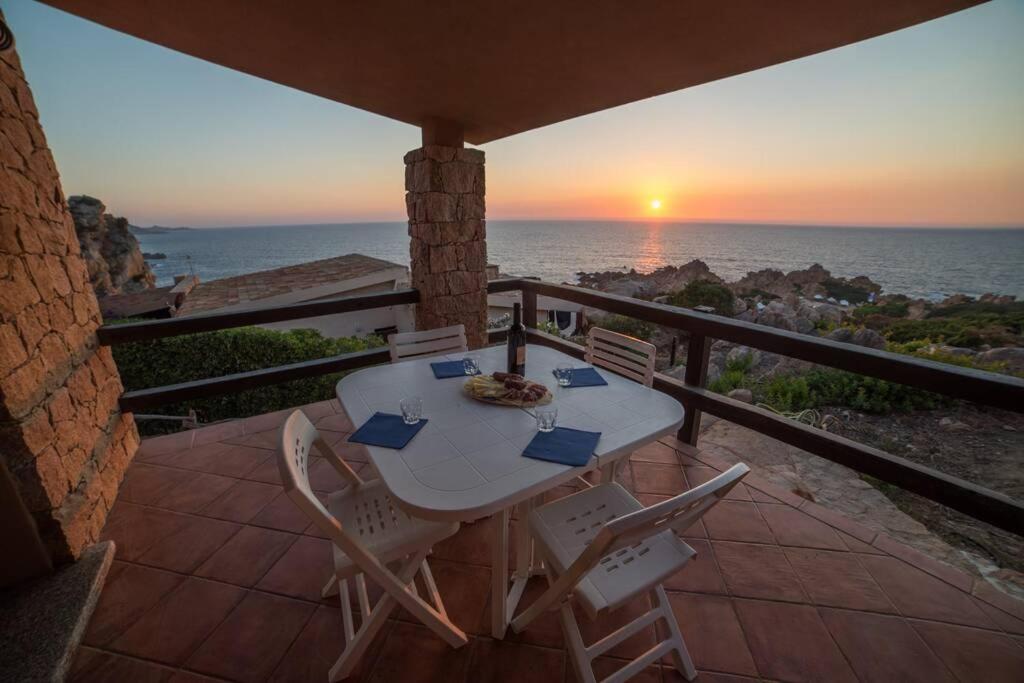 einen Tisch und Stühle auf einem Balkon mit Blick auf den Sonnenuntergang in der Unterkunft Casa Del Tramonto in Costa Paradiso