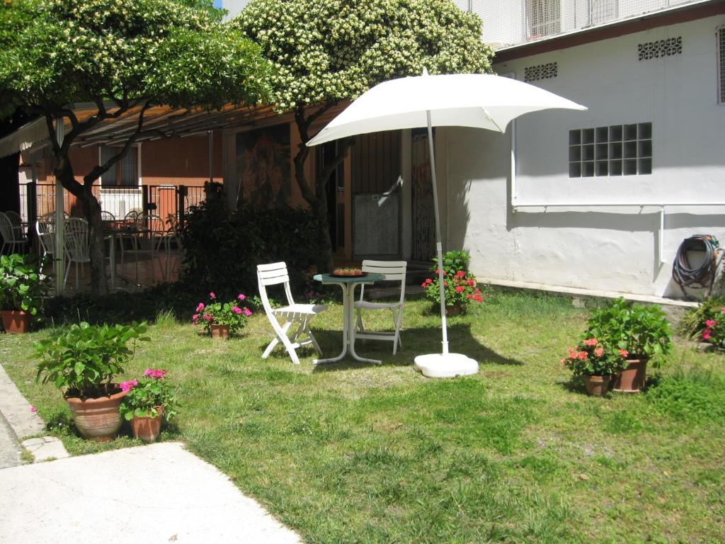 - une table, deux chaises et un parasol dans la cour dans l'établissement Hotel Eleonora, à Rimini