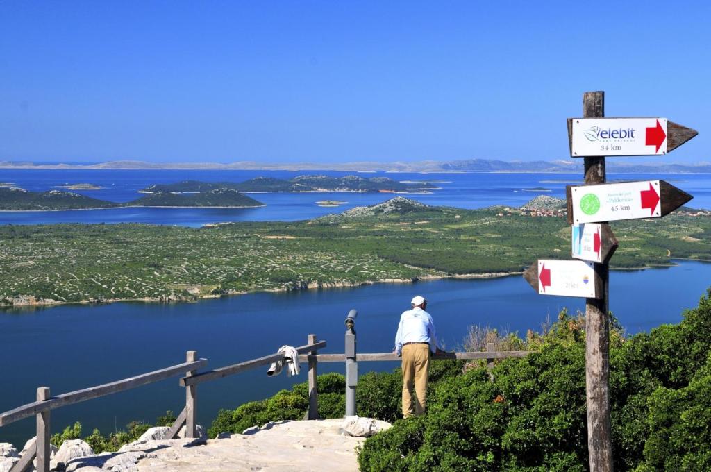 a man standing on top of a mountain with a sign at Apartment in Pakoštane with sea view, balcony, WiFi (3539-2) in Pakoštane