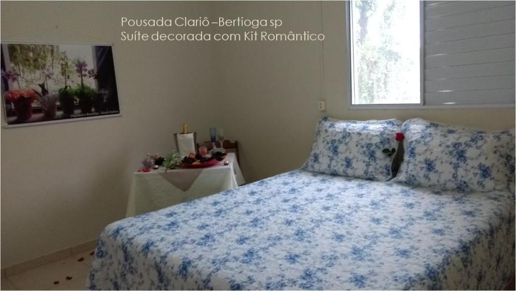 a bedroom with a bed with a blue blanket and a window at Pousada Clariô in Bertioga