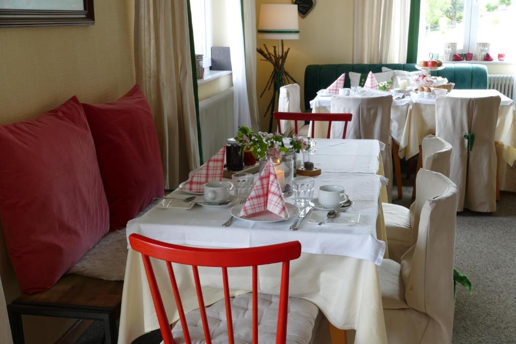 a table with white clothed tables with red chairs at Pension Geissler-Reicher in Oberwölz Stadt