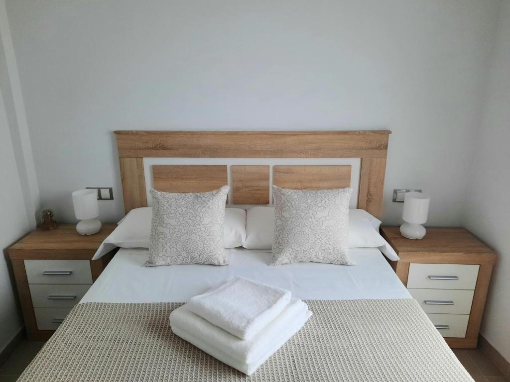 a bedroom with a large white bed with two pillows at Apartamentos Clavero 10 in Plasencia
