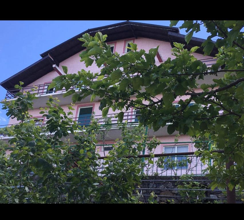 un bâtiment rose avec des arbres devant lui dans l'établissement Sunrise Lindita, à Pukë