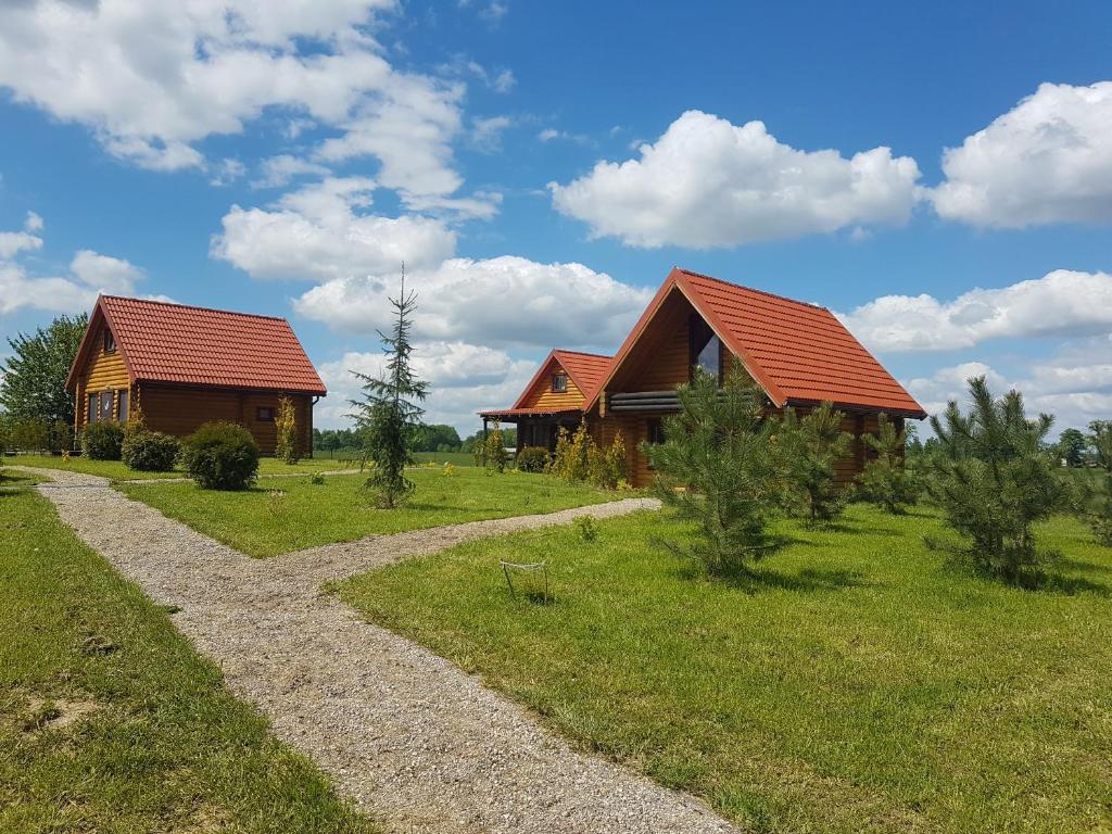 two wooden buildings with red roofs on a field at klub Karino 2 in Mikołajki