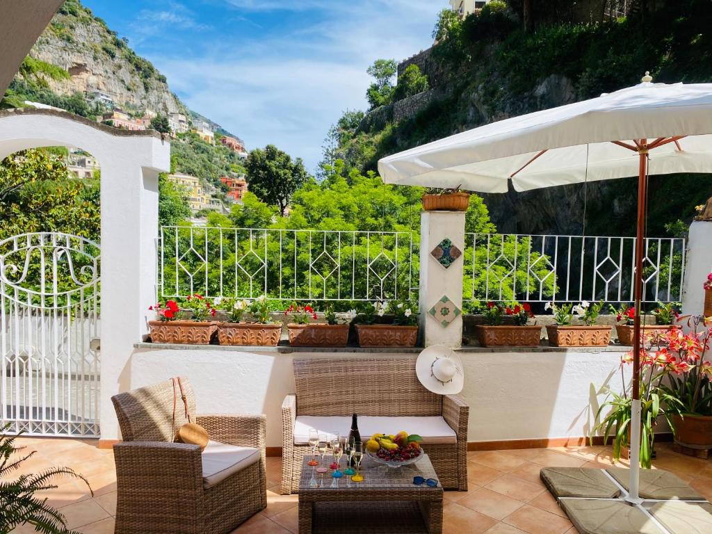 eine Terrasse mit einem Tisch, Stühlen und einem Sonnenschirm in der Unterkunft Casa Angela in Positano