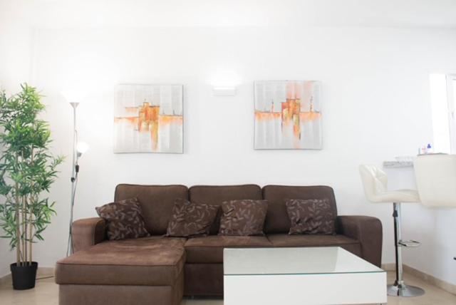 un soggiorno con divano marrone e 2 dipinti di Apartamento Rio Mar a Marbella