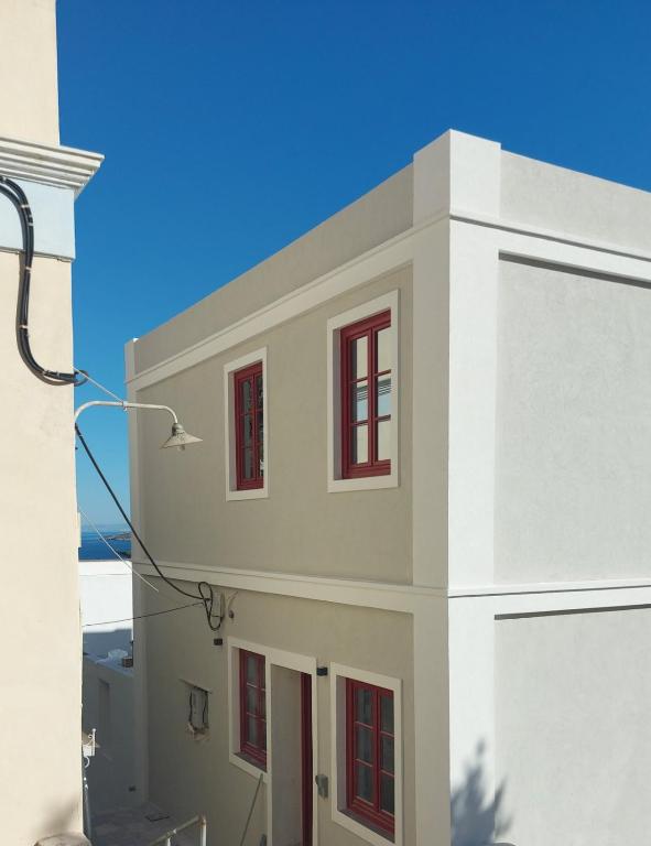 a white building with red windows and a blue sky at Ermoupolis hidden gems in Ermoupoli