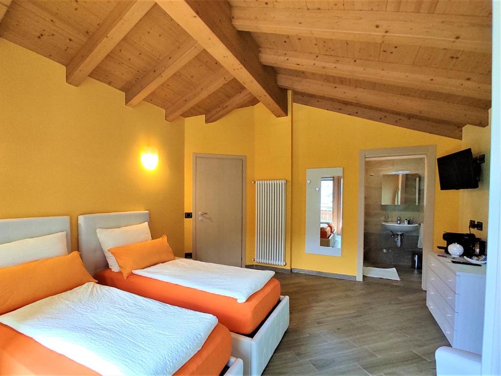 a bedroom with two beds and a bathroom with a sink at B&B Il Germoglio in Castione Andevenno