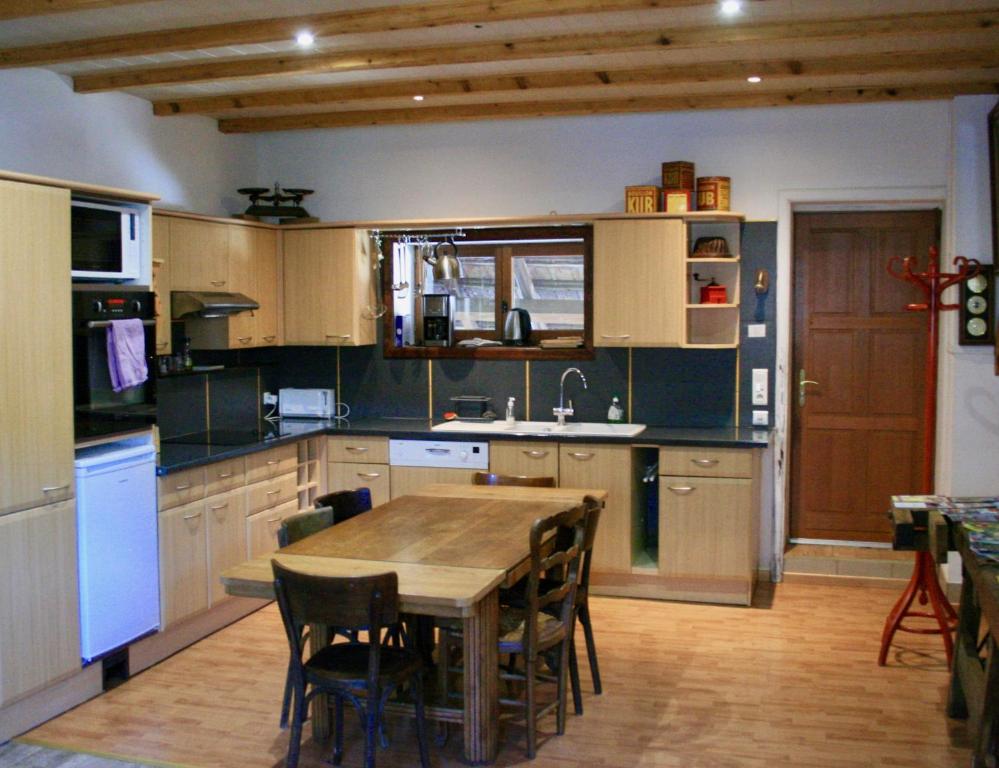 eine große Küche mit einem Holztisch und Stühlen in der Unterkunft grande Cahute in Soultzmatt