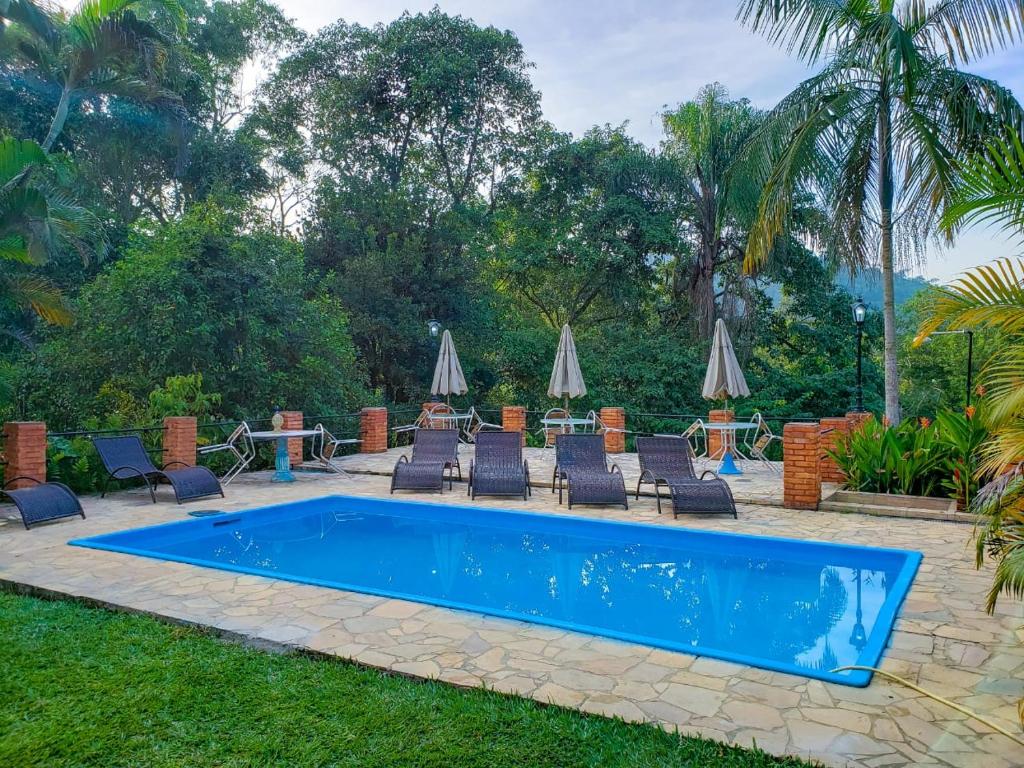 uma piscina com espreguiçadeiras e uma mesa em Pousada Mirante do Penedo em Penedo