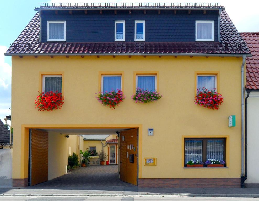 ein gelbes Haus mit Blumenkästen an den Fenstern in der Unterkunft Pension Sigwarth in Belgern
