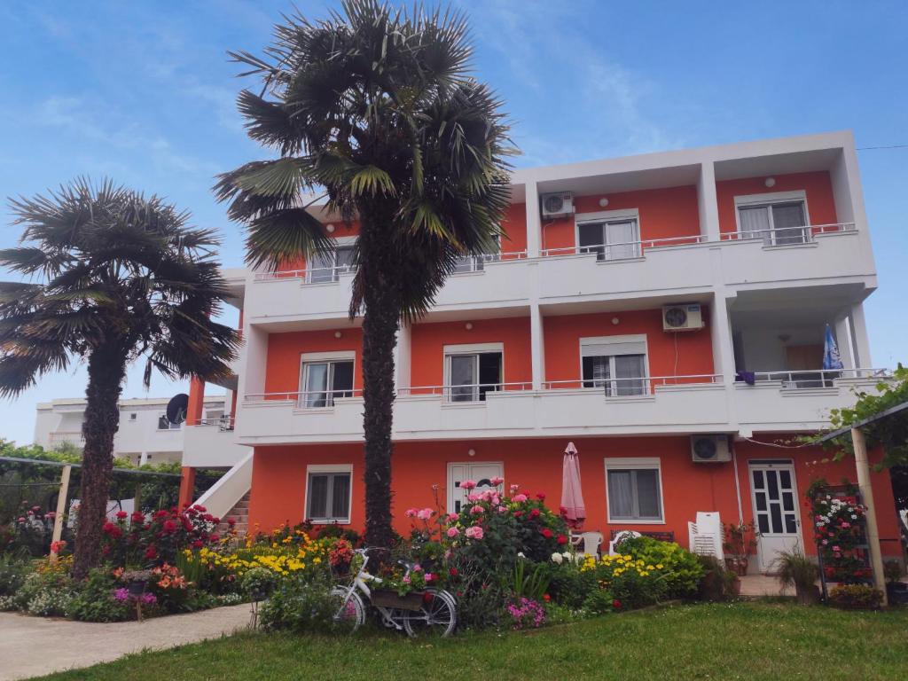 un edificio con palmeras y flores delante de él en Robi Apartments, en Ulcinj