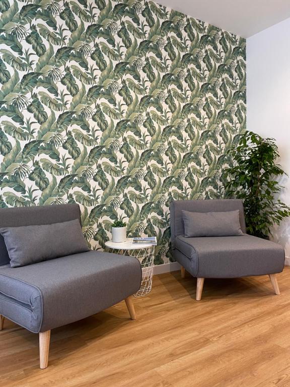 Vento Suites في كالياري: كرسيين في غرفة معيشة وورق جدران أخضر وبيضاء