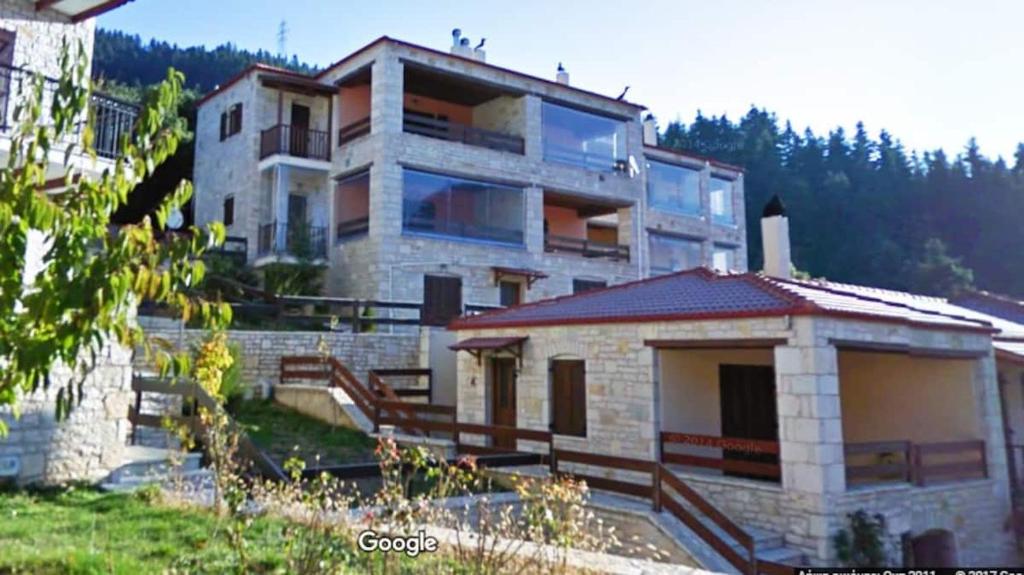 une grande maison avec un escalier en face de celle-ci dans l'établissement La Casa di Pietra, à Karpenísi