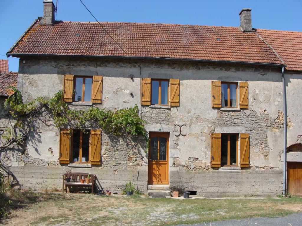 Chambre d'hôtes de puy faucher في Arrènes: منزل حجري قديم بأبواب ونوافذ خشبية