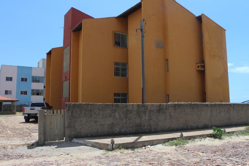 um edifício amarelo com uma cerca em frente em Apartamento de frente para o Mar em Luís Correia em Luís Correia