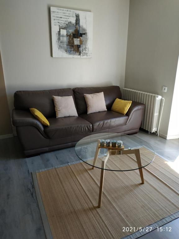 uma sala de estar com um sofá e uma mesa de café em vidro em appartement avec terrasse em Aurillac