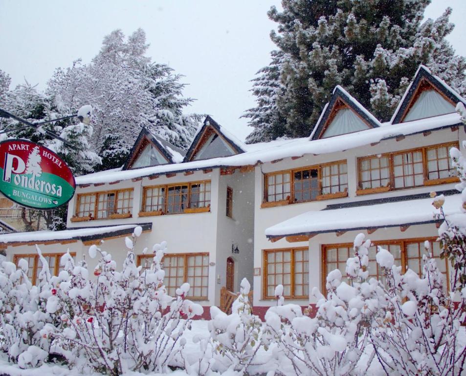 a snow covered building with a sign in front of it at LA PONDEROSA Apart Hotel in San Carlos de Bariloche