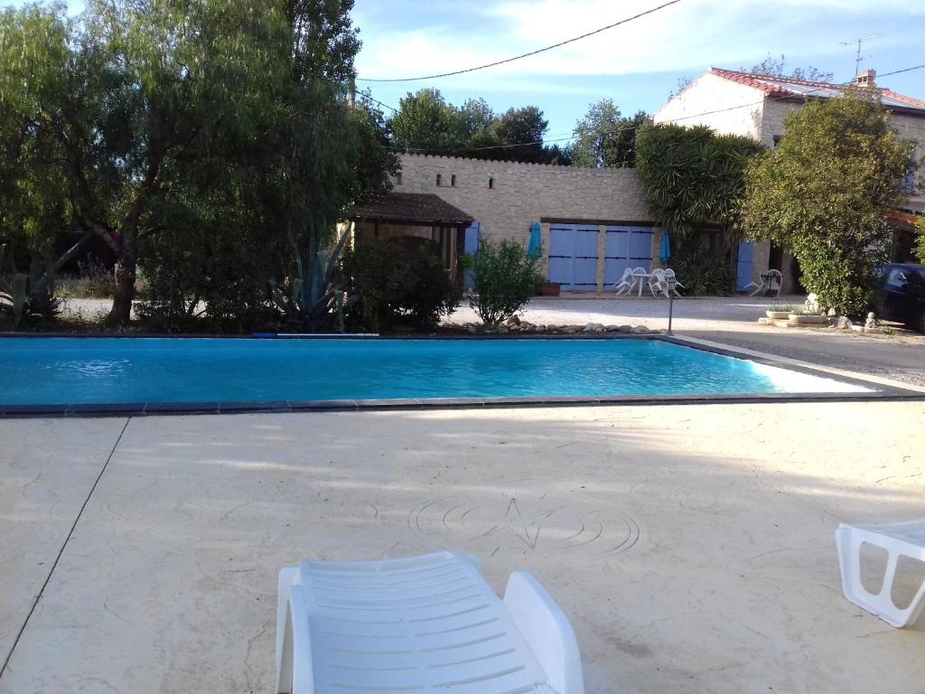 a swimming pool with two white chairs in front of a house at Mas de l'Olivier in Saint-Estève