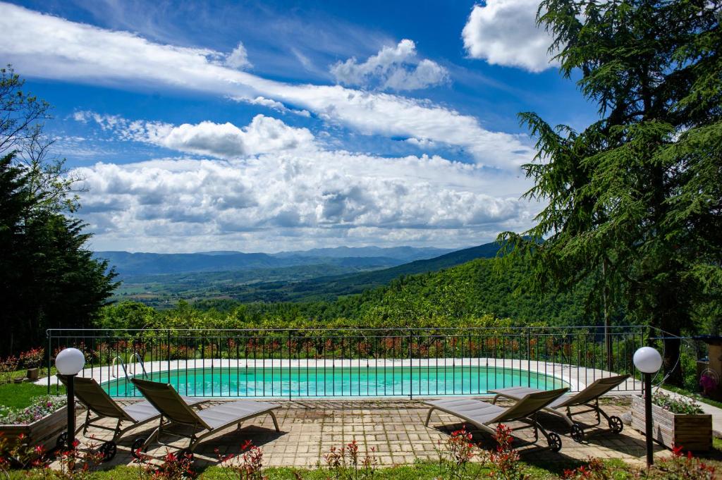 una piscina con sillas y montañas en el fondo en Villa Giuliana B&B, en Scarperia
