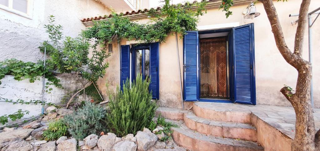 a house with blue shutters and stairs leading to a door at Traditional Hillside Cottage in Gythio