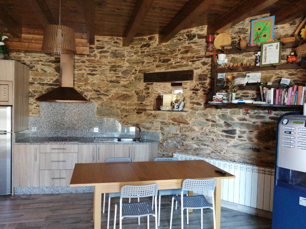 cocina con mesa de madera y sillas en Albergue Pension Porta Santa en Baleira