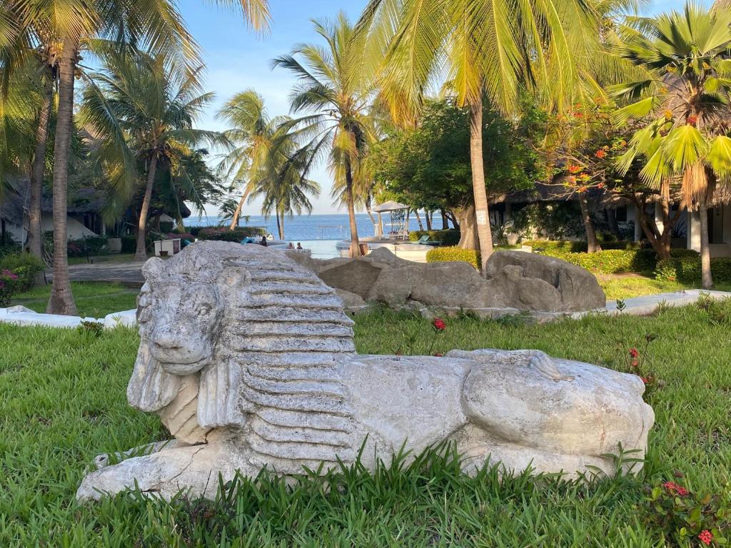 une statue de lion en pierre dans l'herbe près de la plage dans l'établissement White Lion, à Malindi