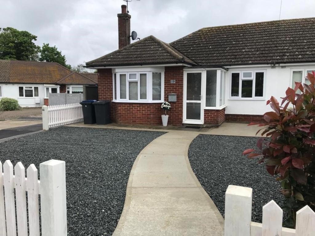 a house with a white fence and a driveway at Oyster Beach Cottage in Whitstable