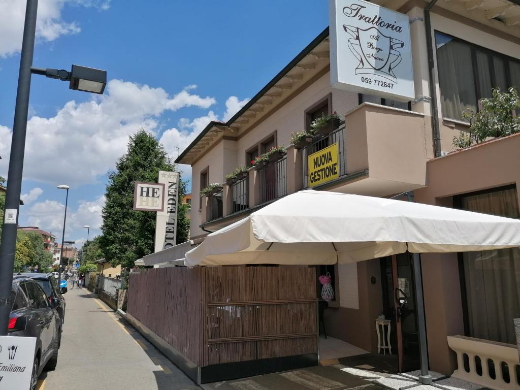 a building with a white umbrella outside of it at Hotel Eden in Vignola