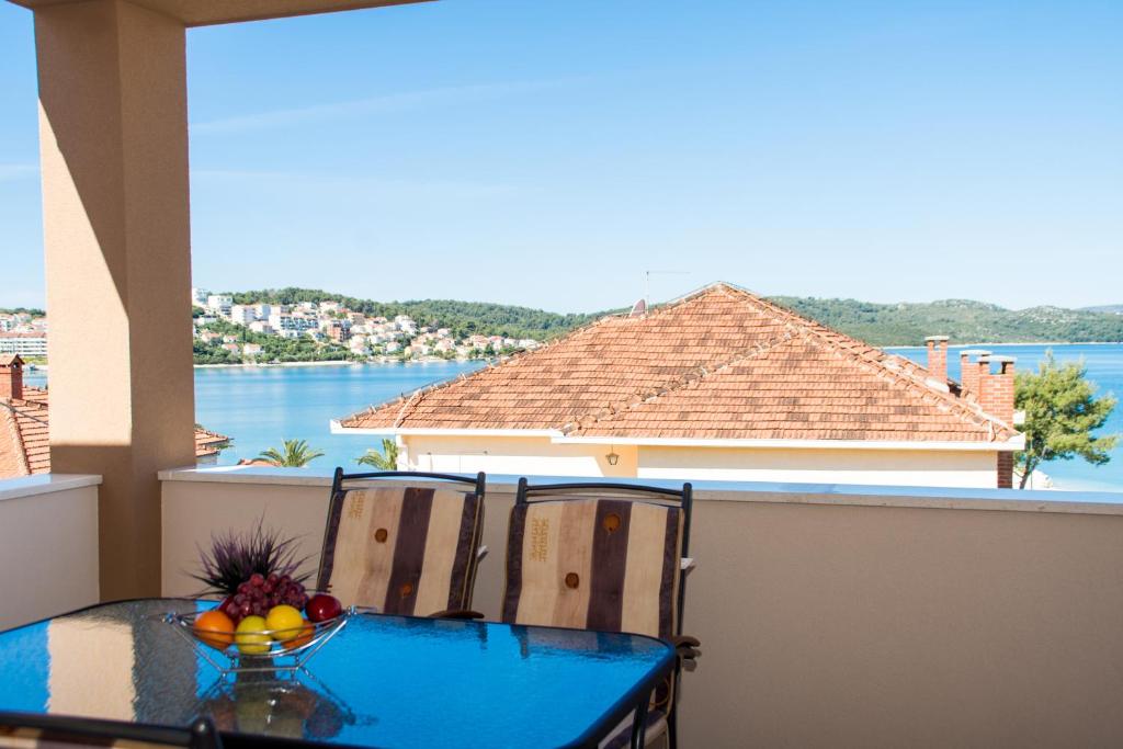 einen Tisch und Stühle auf einem Balkon mit Blick auf das Wasser in der Unterkunft Apartments Ploka in Trogir