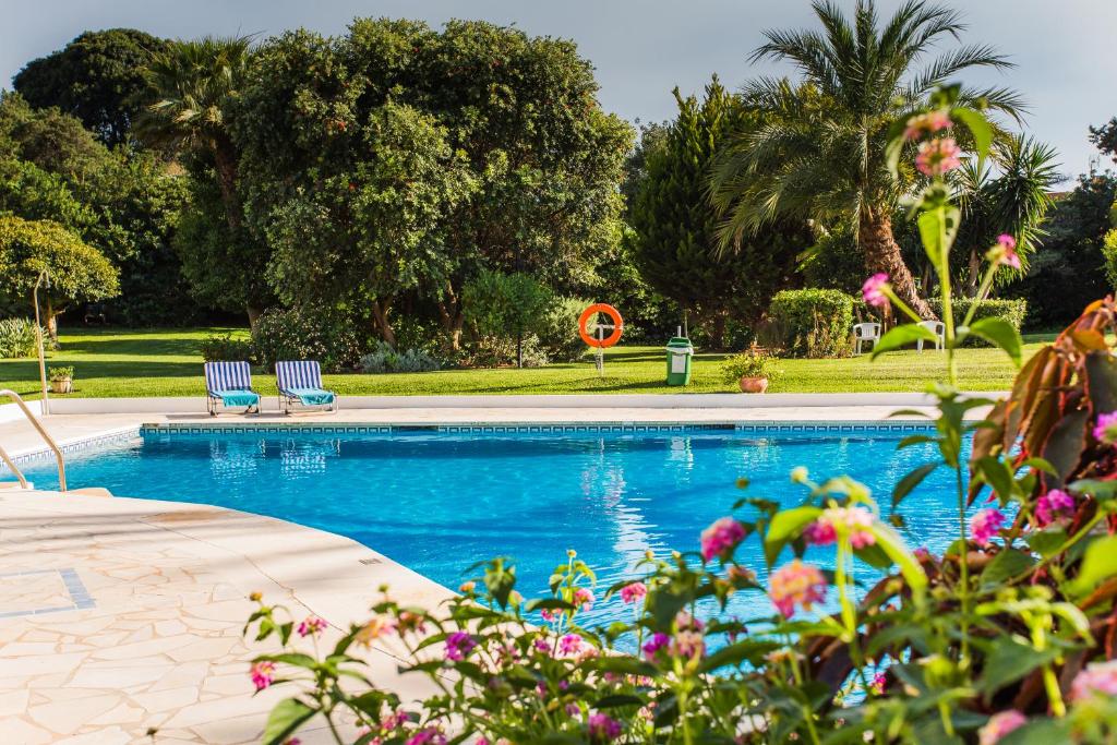 una piscina con 2 sillas y flores en Suite Bora Bora, en Marbella