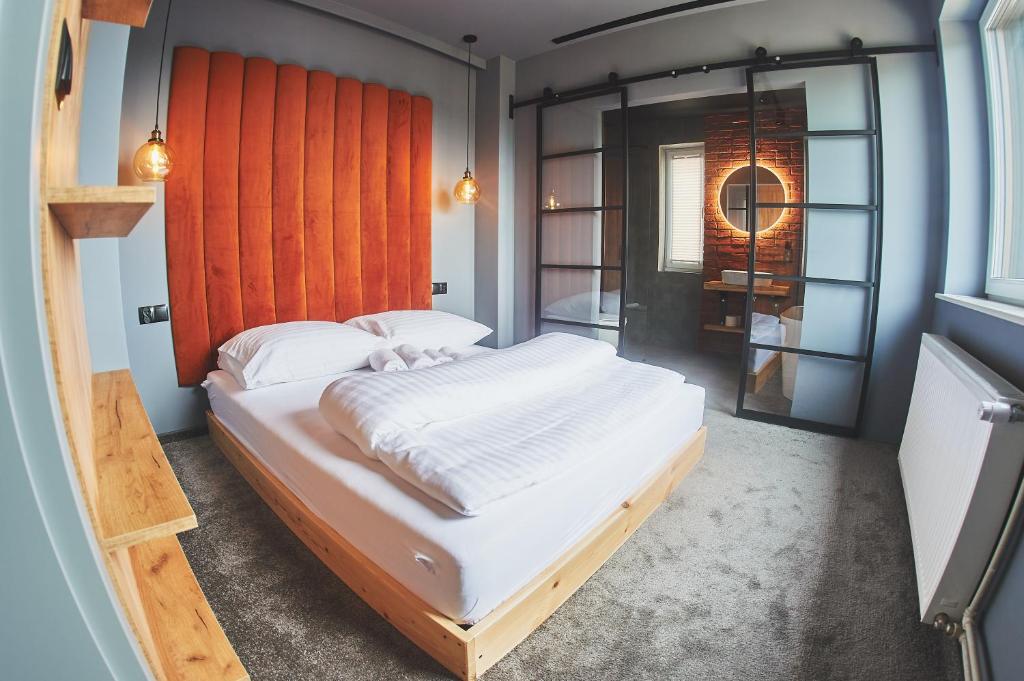 a bedroom with a large white bed with an orange headboard at Studio Loft Winnica Sopel in Ziewanice