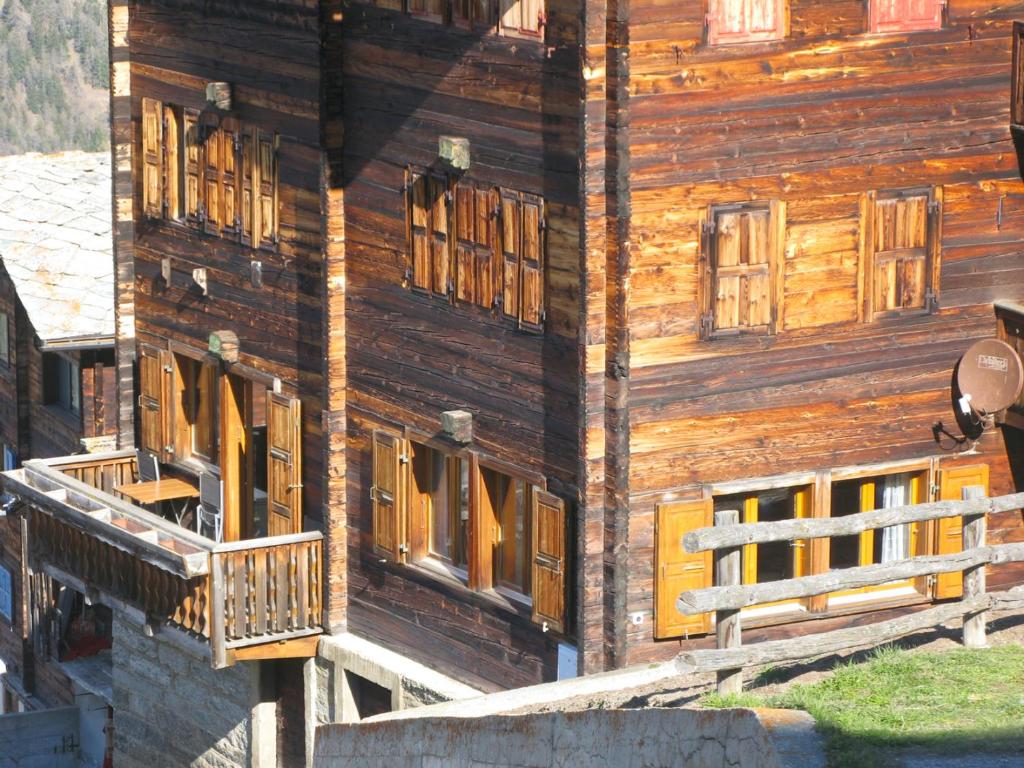 Alpia 26 - Zwei Zimmerwohnung in traditionellem Walliser Haus في Gasenried: مبنى خشبي شبابيكه وشرفه