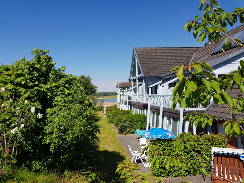 ein Gebäude mit einem blauen Regenschirm, einem Tisch und Stühlen in der Unterkunft Fewo 2 im Fischerhaus mit Terrasse in Ostseebad Sellin