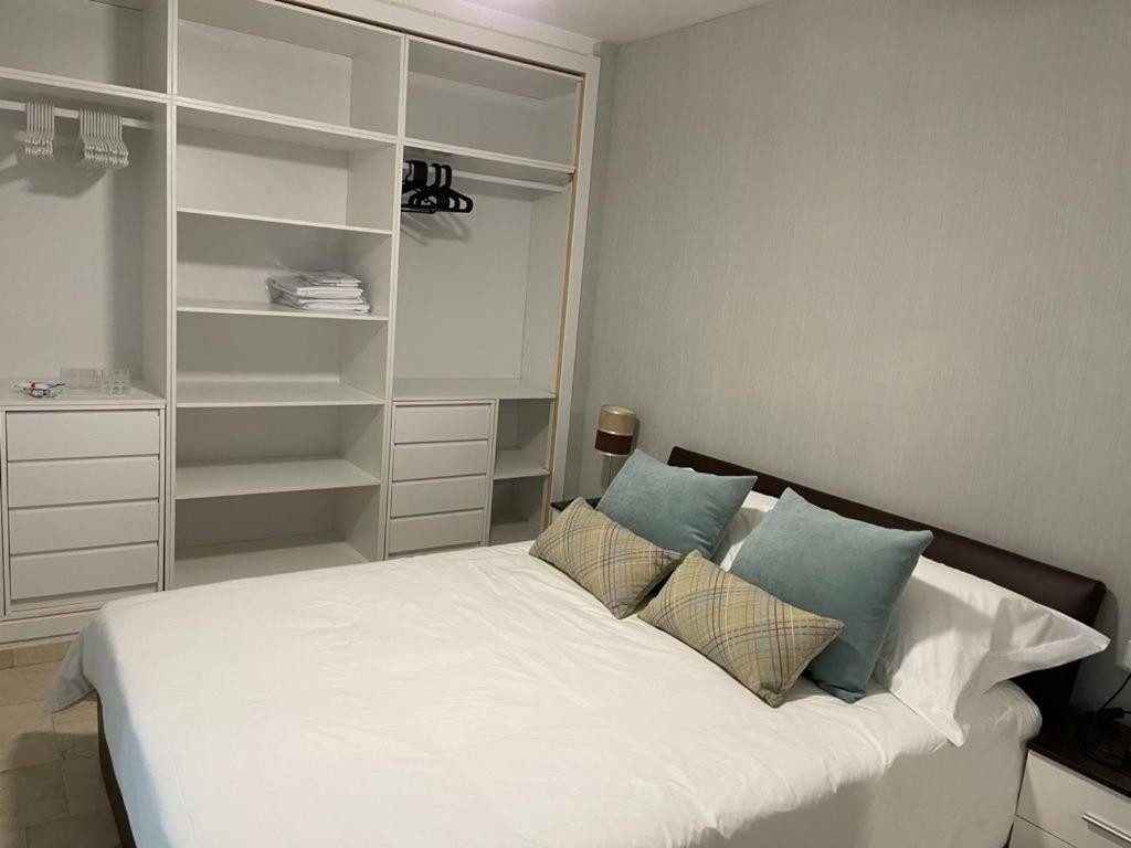 sypialnia z białym łóżkiem z poduszkami i półkami w obiekcie Apartamento Rio Mar w Marbelli