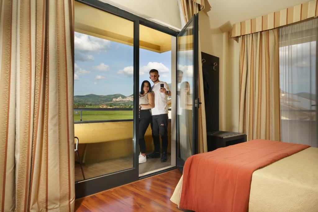 un hombre y una mujer parados en una habitación con ventana en Hotel Cristallo, en Asís