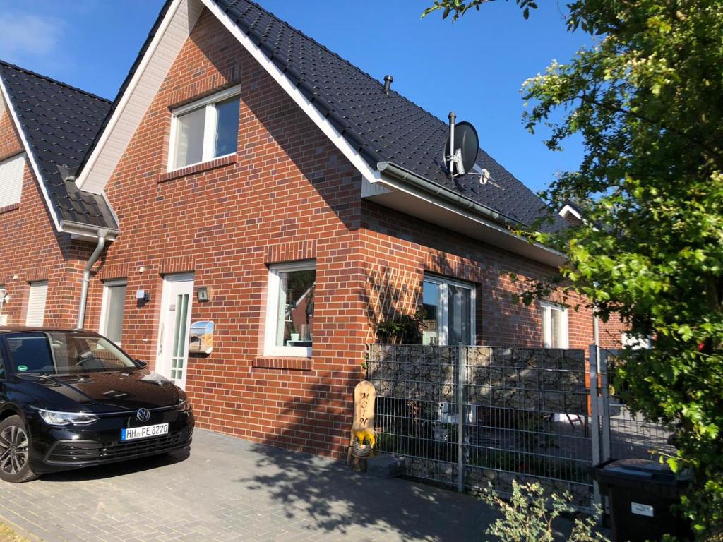 a black car parked in front of a brick house at Haus Willy Dornum mit Wintergarten und Wallbox in Dornum