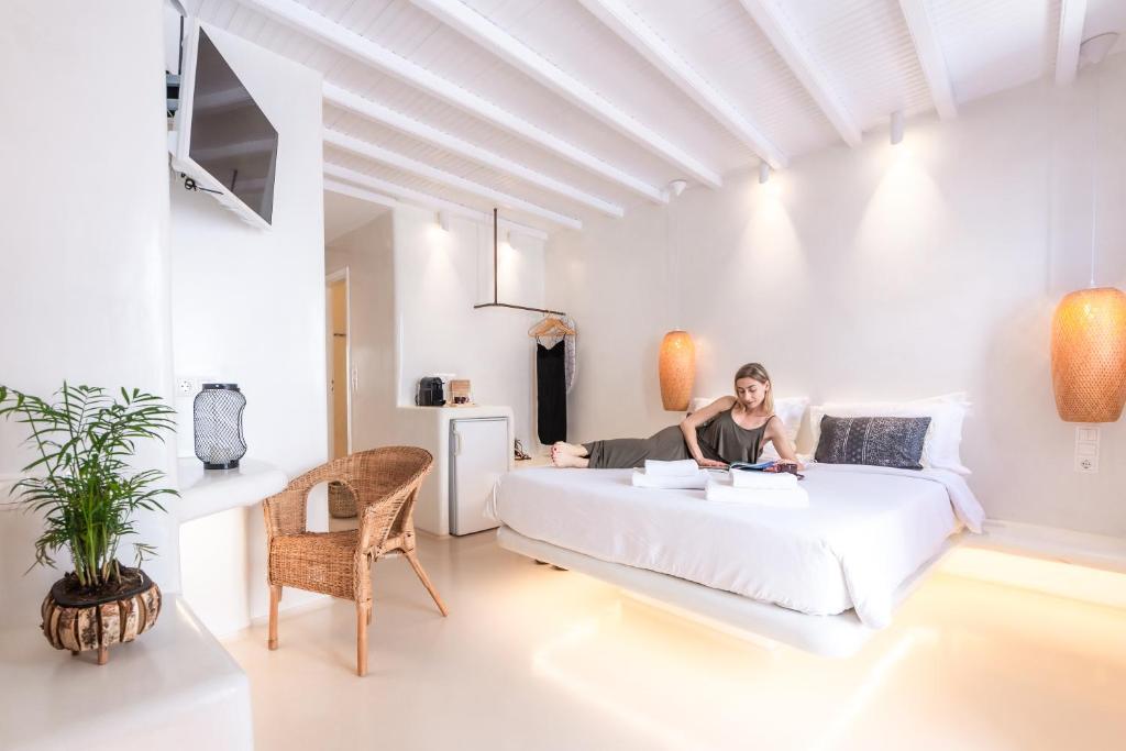 Anastasia's Visage Stylish Accommodation Rooms City Centre Mykonos في مدينة ميكونوس: امرأة تجلس على سرير في غرفة