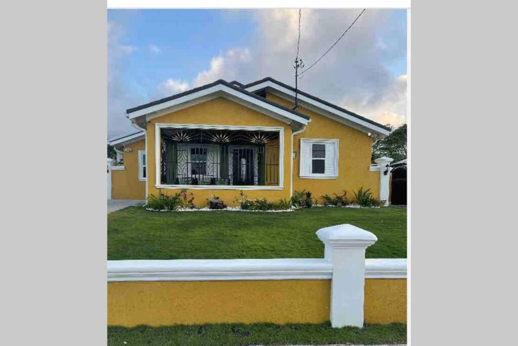 una casa amarilla con una valla delante de ella en Villa Kalaya en Mammee Bay