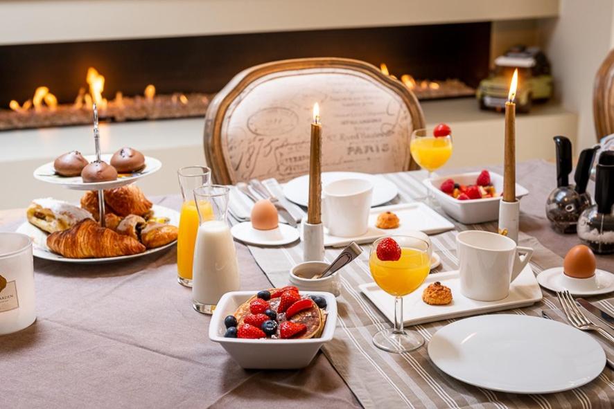 una mesa con desayuno, bebidas y una chimenea en Adamas B&B, en Dendermonde