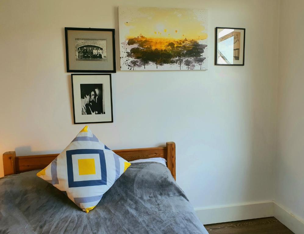 - une chambre dotée d'un lit avec des photos sur le mur dans l'établissement Home In Queen's Park, à Londres