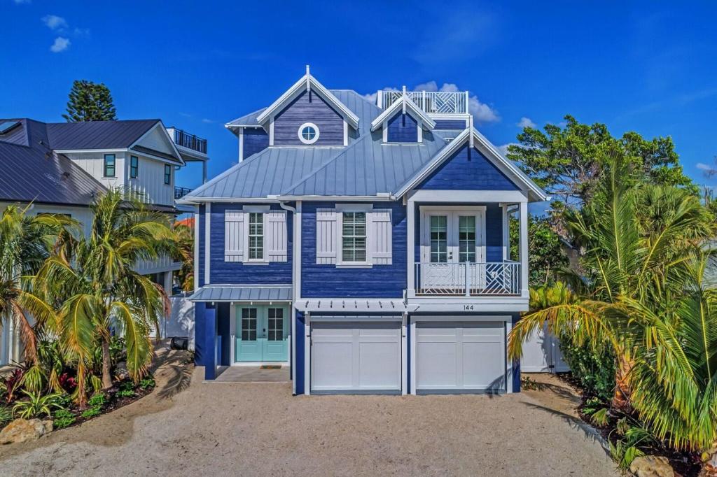 una casa azul en la playa con palmeras en Casa Amiga by Beach Retreats, en Anna Maria
