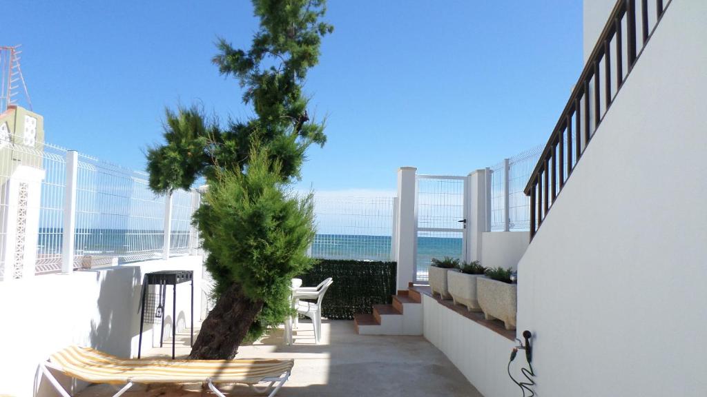 デニアにあるApartamento primera linea de playa WIFI gratisの木と椅子が備わるバルコニーと海