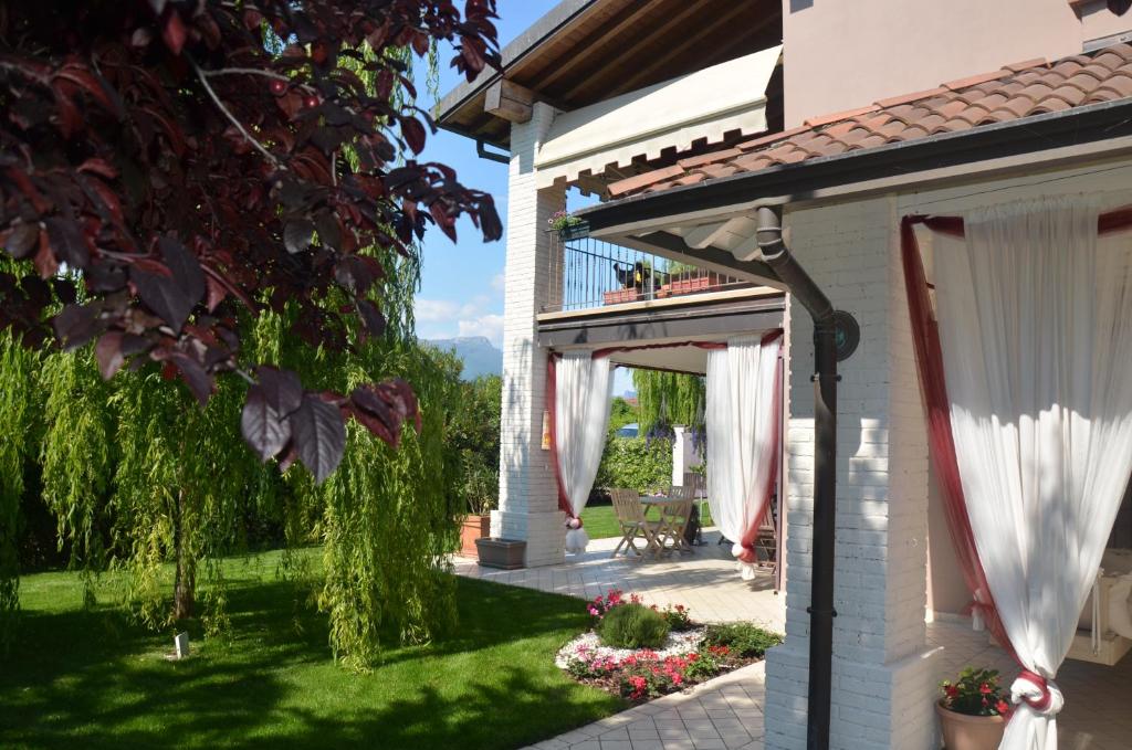 a house with white curtains and a patio at Asso Bed & Breakfast in Manerba del Garda